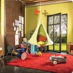 White Floating Teepee Chair hammock in kids play room surrounded by toy drum set airplane basketball, stuffed animal near a large open window door