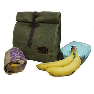  Forest green waxed canvas bag next to two bananas fast food paper bag and glass tupperware container 