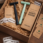 Safety razors and blades in a cardboard box on a wooden surface
